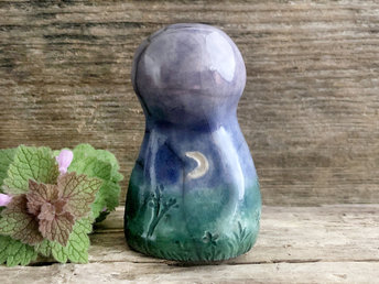 Raku ceramic earth spirit spirit sculpture glazed in forest green, blue, and violet (bottom to top). It has plant shapes and flowers carved into it and a white crescent moon carving too.
