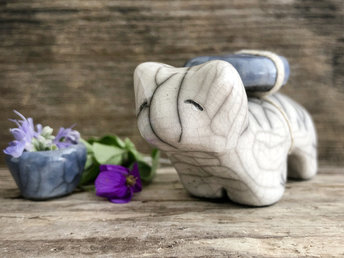 Raku ceramic white bear sculpture with a kind, gentle face. She carries a blue ceramic crescent moon on her back and has a little blue bowl too.