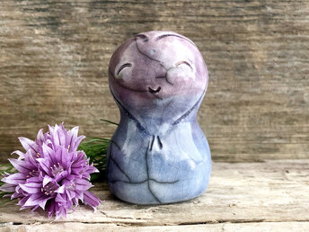 A smiley and loving Jizo Shinto raku ceramic sculpture talisman in soft blue and purple with a heart shape around her kind, smiling face. A wonderful smooth shape to hold in the hand.