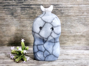 A kodama nature and forest spirit kami ceramic raku sculpture glazed in a bottom-to-top gradient of soft blue to almost white. It has a gentle face, and a white crescent moon on its head.