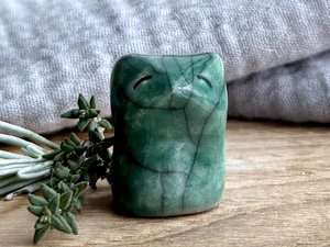 very small raku ceramic fox sculpture glazed in a forest-green colour. it has a gentle face.