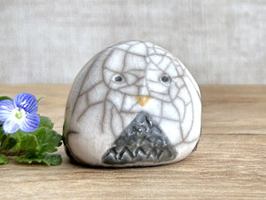 Raku ceramic little owl or owlet kami nature spirit statue glazed in white with a grey front and lots of raku crackles. it has gentle eyes and a little golden yellow beak.