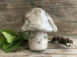 Sweet little mushroom raku ceramic sculpture with a very smiley face. His stalk is glazed in creamy-white (this is where his face is) and his mushroom cap is pale grey-brown.