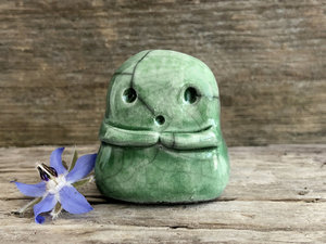 A sweet little kodama nature spirit ceramic guardian statue glazed in shades of green and with a lovely, gentle face and little arms.