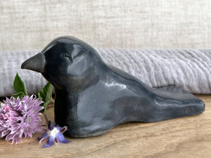  Raku ceramic sculpture of a sitting raven. It is glazed in dark blue-grey, and its beak is left natural, unglazed black.