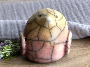chonky raku ceramic bird sculpture glazed in a top-to-bottom gradient of pale golden yellow to pale peach to pale pinky red. it has a kind, gentle, and slightly concerned face and feels very reassuring to hold. it has two little wings at its sides folded flat to its body.