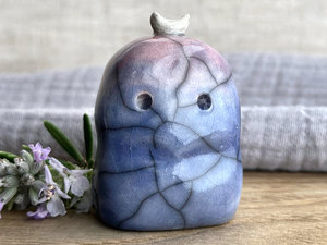 A kodama forest spirit kami ceramic raku sculpture glazed in a bottom-to-top gradient of blue to soft mauve. It has a gentle face, and a white crescent moon on its head.