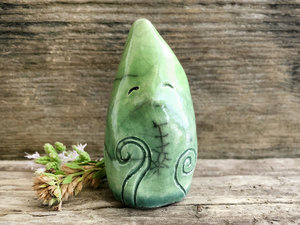Raku ceramic sculpture of an elemental earth spirit being. It is very friendly, and it's glazed in a bottom-to-top gradient from forest green to spring green. It has Celtic spiral and plant carvings on its body.