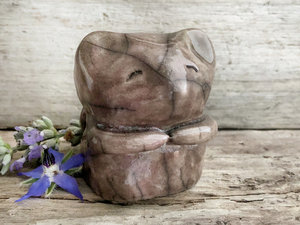 raku ceramic sculpture of a sweet little mouse. it's glazed in warn brown with a hint of mauve on the left side. it has two cute little arms, a happy, gently smiling face, and a long tail curled up on its back.