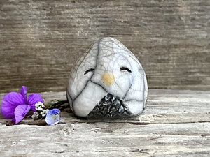Raku ceramic little owl or owlet kami nature spirit statue glazed in white and grey-brown with gentle, smiling eyes and a little yellow beak.