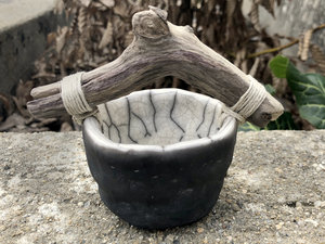 Small raku ceramic bucket with a driftwood handle. The bucket is glazed white on the inside and left natural, unglazed black on the outside.