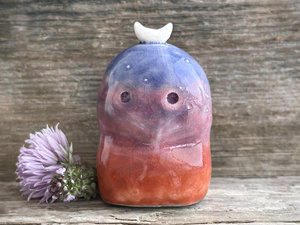 A kodama nature and forest spirit kami ceramic raku sculpture glazed in a bottom-to-top gradient of burnt red-orange to mauve to purple to indigo. It has a gentle face, some small white marks like stars on its head, and a white crescent moon on top.