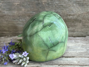 vaguely egg-shaped but quite round and stout nature spirit sculpture. it is glazed in a bottom-to-top gradient of yellow-green to spring green and looks a little like a frog. it has a gentle, happy face.
