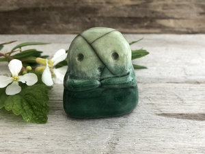 A sweet little kodama nature spirit ceramic guardian statue glazed in shades of green and with a lovely, gentle face and little arms.