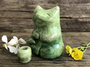 Raku ceramic sculpture of a fox sitting in a meditation position. He is glazed in beautiful spring greens, and he has little praying hands (paws). His face is very kind and gentle.
