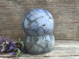 a smiley and loving Jizo Shinto raku ceramic sculpture talisman glazed in a bottom-to-top gradient of grey to blue. they have a kind, gentle face and are a wonderful smooth shape to hold in the hand.