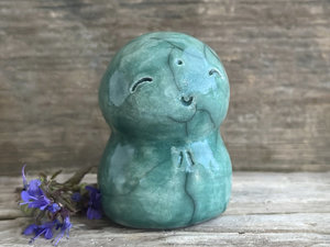 a smiley and loving Jizo Shinto raku ceramic sculpture talisman glazed in forest green. they have a kind, gentle face and are a wonderful smooth shape to hold in the hand.