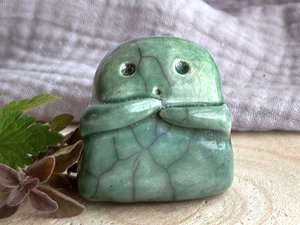 A sweet little kodama nature spirit ceramic guardian statue glazed in shades of green and with a lovely, gentle face and little arms.