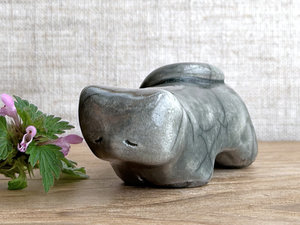 Little raku ceramic cat spirit kami sculpture glazed in grey. It has a kind, gentle, sleepy face, and its tail is curled over its back on the left.