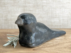  Raku ceramic sculpture of a sitting raven. It is glazed in dark blue-grey, and its beak is left natural, unglazed black.