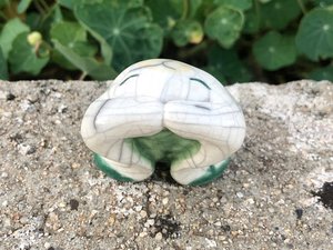 Rake ceramic sculpture of a frog or toad. He is glazed in white with green grass and plant designs. He looks very sweet and friendly, lovely for a Shinto shrine or shamanism.
