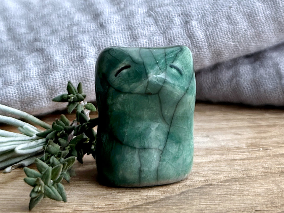 very small raku ceramic fox sculpture glazed in a forest-green colour. it has a gentle face.