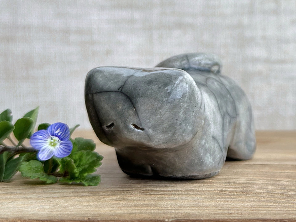 Little raku ceramic cat spirit kami sculpture glazed in grey. It has a kind, gentle, sleepy face, and its tail is curled over its back on its right.