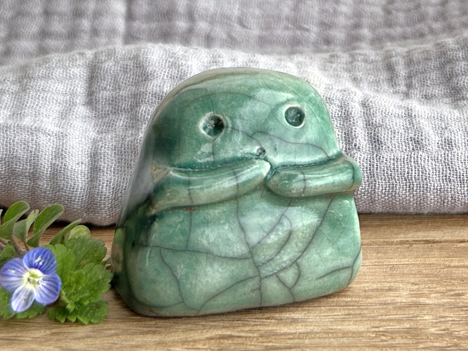 A sweet little kodama nature spirit ceramic guardian statue glazed in a soft forest green and with a lovely, gentle face and little arms.