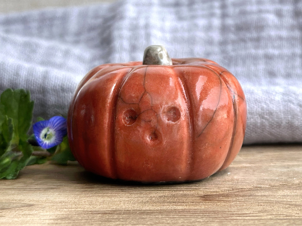 Raku ceramic orange pumpkin nature spirit sculpture with a cute and stunned-looking face.