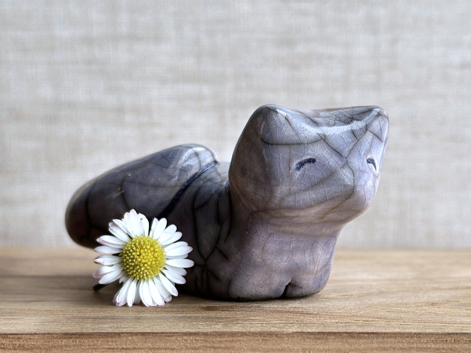 raku ceramic kitsune fox sculpture glazed in pale violet. it has a kind, gentle face, and a tail curled over its back on its right side.