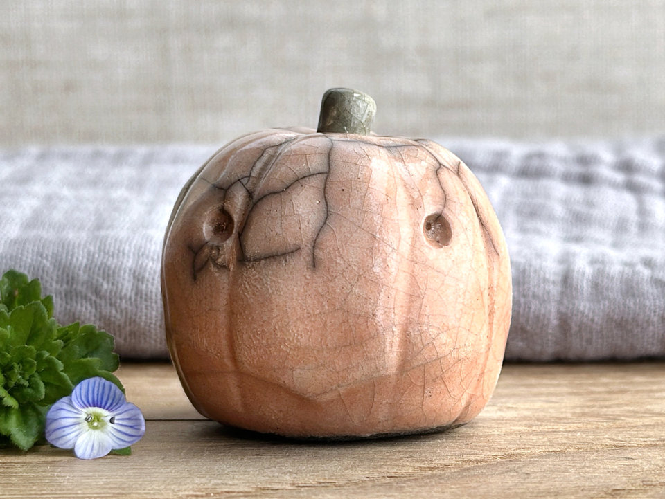 raku ceramic pale orange pumpkin nature spirit sculpture with a somewhat uncertain, worried look on its face. it has a cute little green-brown stalk on top.