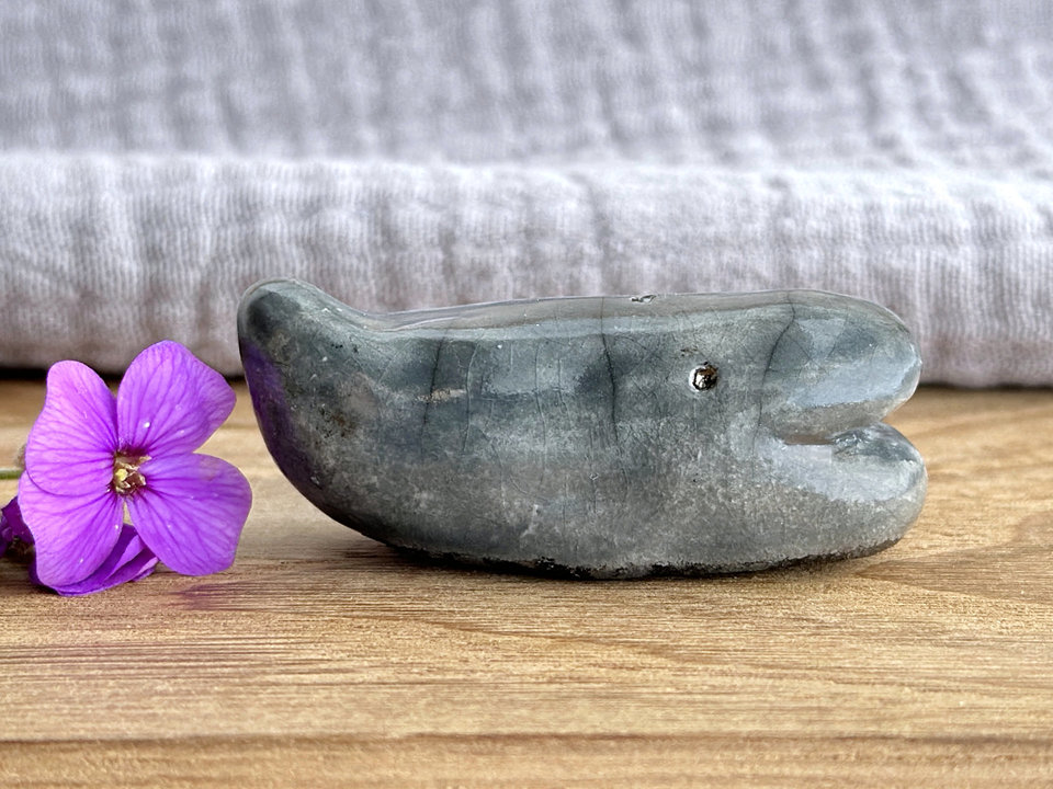 a small, blue-grey whale sculpture. its small tail is raised up, and it has a gently smiley sort of face.