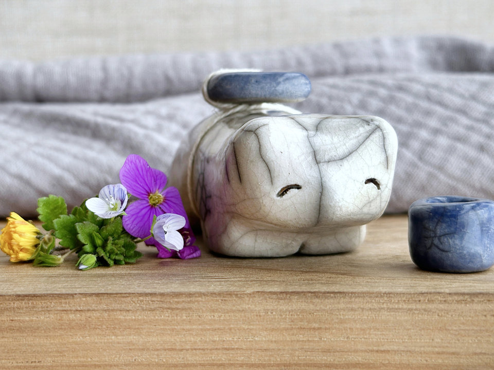 Raku ceramic white bear sculpture with a kind, gentle face. It carries a blue ceramic crescent moon on its back and has a little blue bowl too.