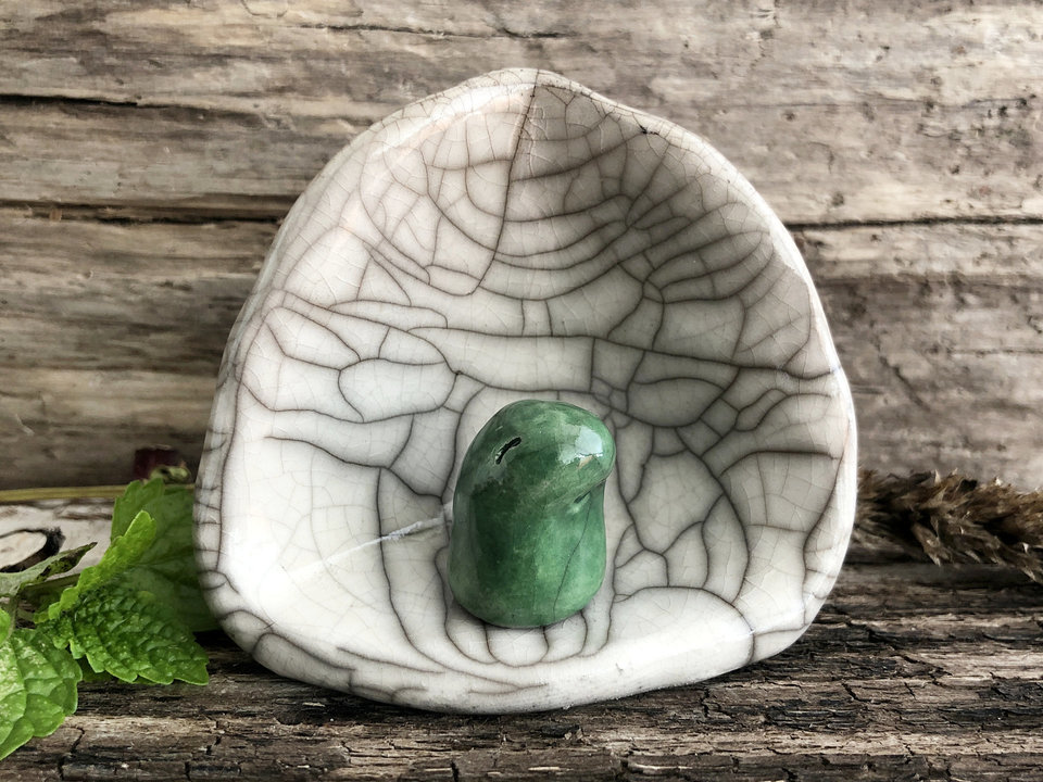 A Shinto kodama nature spirit kami of forests and trees in his own little kamidana shine. The kodama is very sweet and glazed in green. The shrine is white with beautiful raku patterns and vaguely egg-shaped.