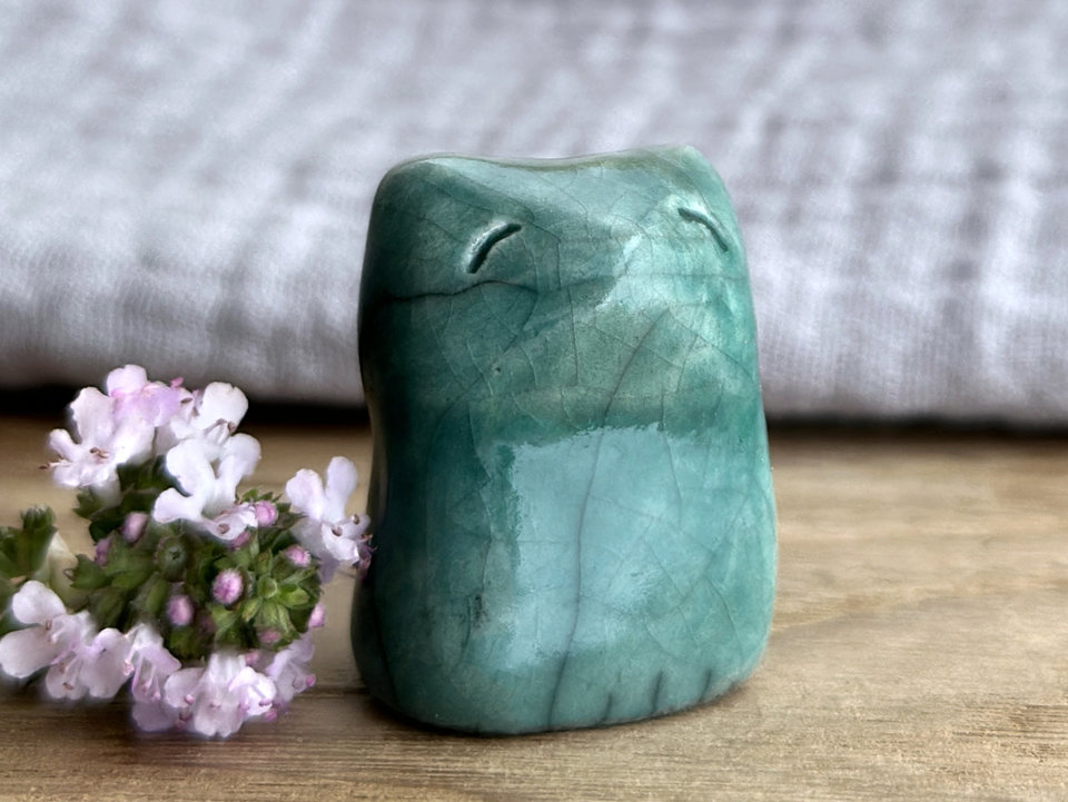very small raku ceramic fox sculpture glazed in a forest-green colour. it has a gentle face.