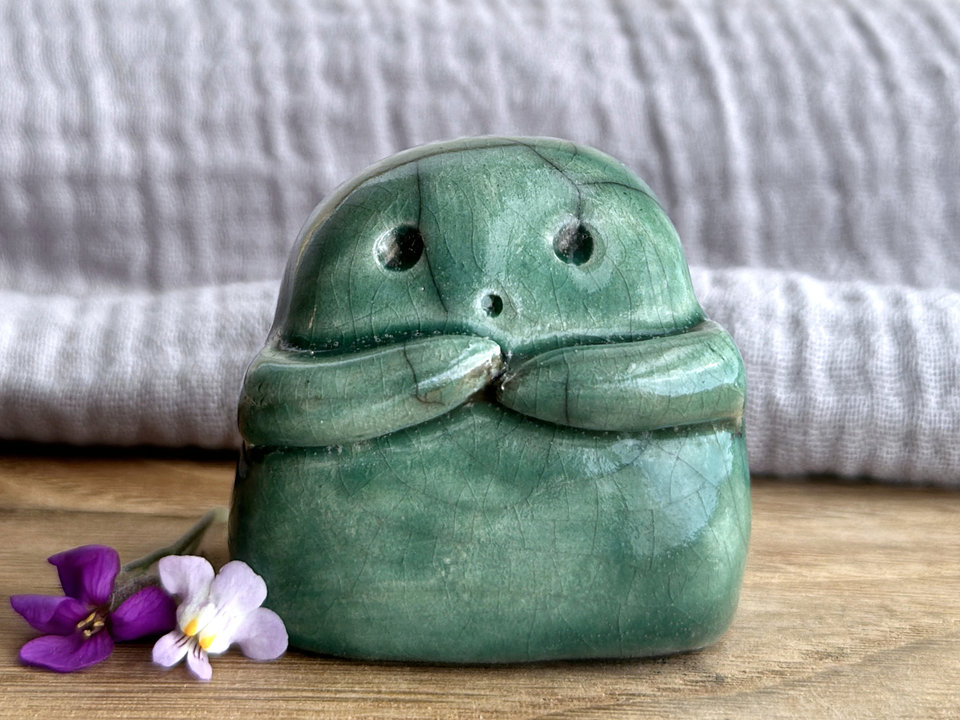 A sweet little kodama nature spirit ceramic guardian statue glazed in forest green and with a lovely, gentle face and little arms.