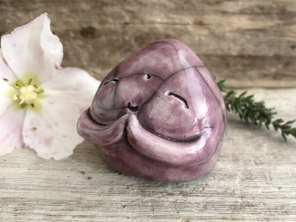 A smiley, loving, and very happy Jizo Shinto raku ceramic sculpture talisman glazed in a warm plum colour with sweet little praying hands.
