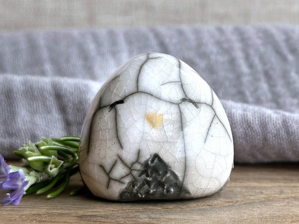 Raku ceramic little owl or owlet kami nature spirit statue glazed in white and grey with gentle, smiling eyes and a little golden yellow beak. It's a very compact shape and lovely to hold in the hand.