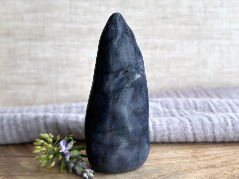 Raku ceramic sculpture of a tall, pointy gnome. It's glazed in dark bleu-grey and has a kind but almost solemn, quiet face.