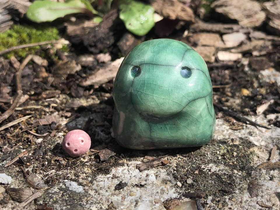 Ceramic raku nature kodama spirit glazed in green with a small, round, pink elemental spirit friend.
