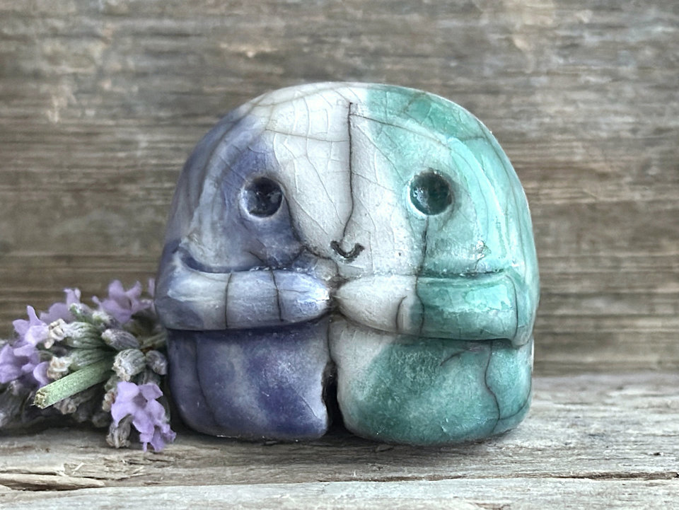A sweet little nature spirit ceramic guardian statue glazed in the men's gay flag green, white, and blue colours and with a lovely, gentle face and little arms. It has a small branch design carved up one side.
