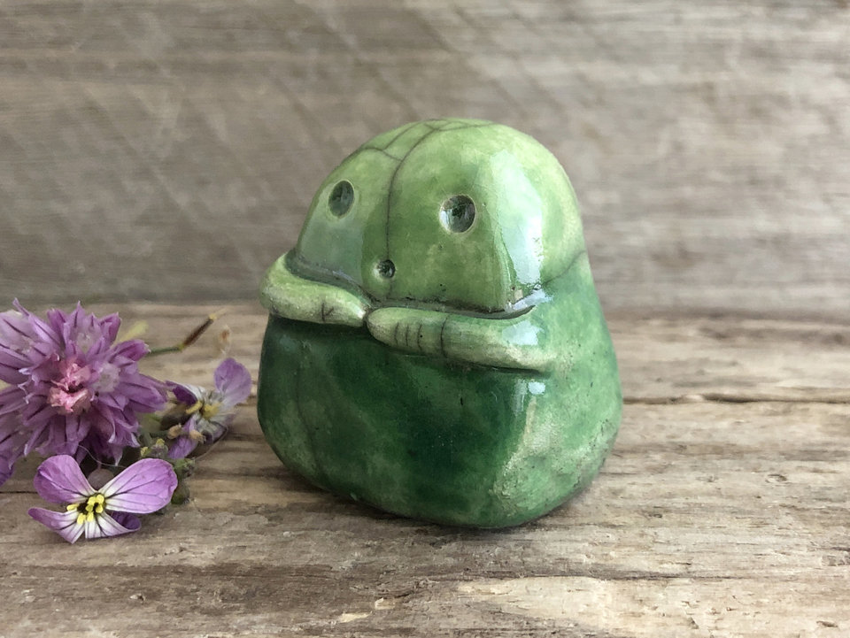 A sweet little kodama nature spirit ceramic guardian statue glazed in shades of green and with a lovely, gentle face and little arms.
