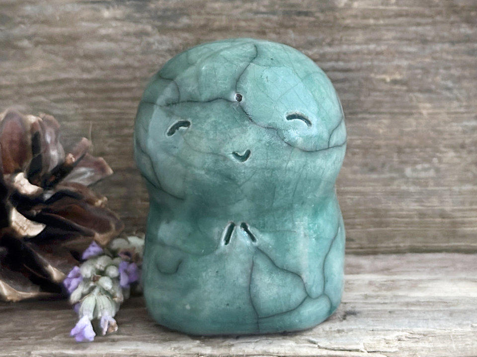 a smiley and loving Jizo Shinto raku ceramic sculpture talisman glazed in forest green. they have a kind, gentle face and are a wonderful smooth shape to hold in the hand.