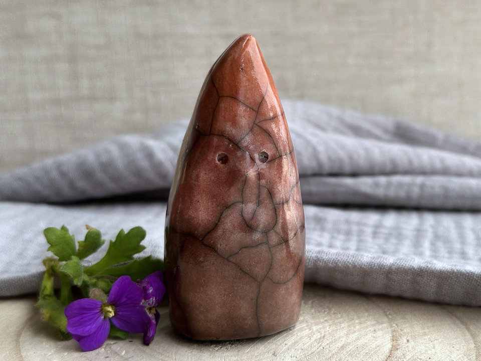 Raku ceramic sculpture of a tall, pointy gnome glazed in a bottom-to-top gradient of brown to bordeaux red to warm orange.