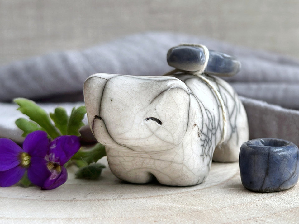 Raku ceramic white bear sculpture with a kind, gentle face. It carries a blue ceramic crescent moon on its back and has a little blue bowl too.