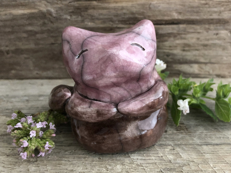 Raku ceramic sitting fox glazed in soft gradient from brown to pinky mauve. He has a sweet face, and two little arms across his front, and he looks very happy and contented. He's also a little chonky.
