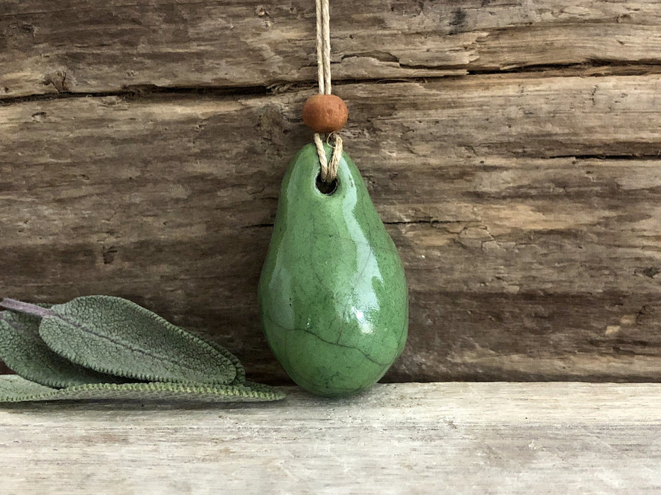 Raku ceramic worry pendant shaped a little like a bendy pear and glazed in green. It has a sandalwood bead above it and is strung on a flax cord.