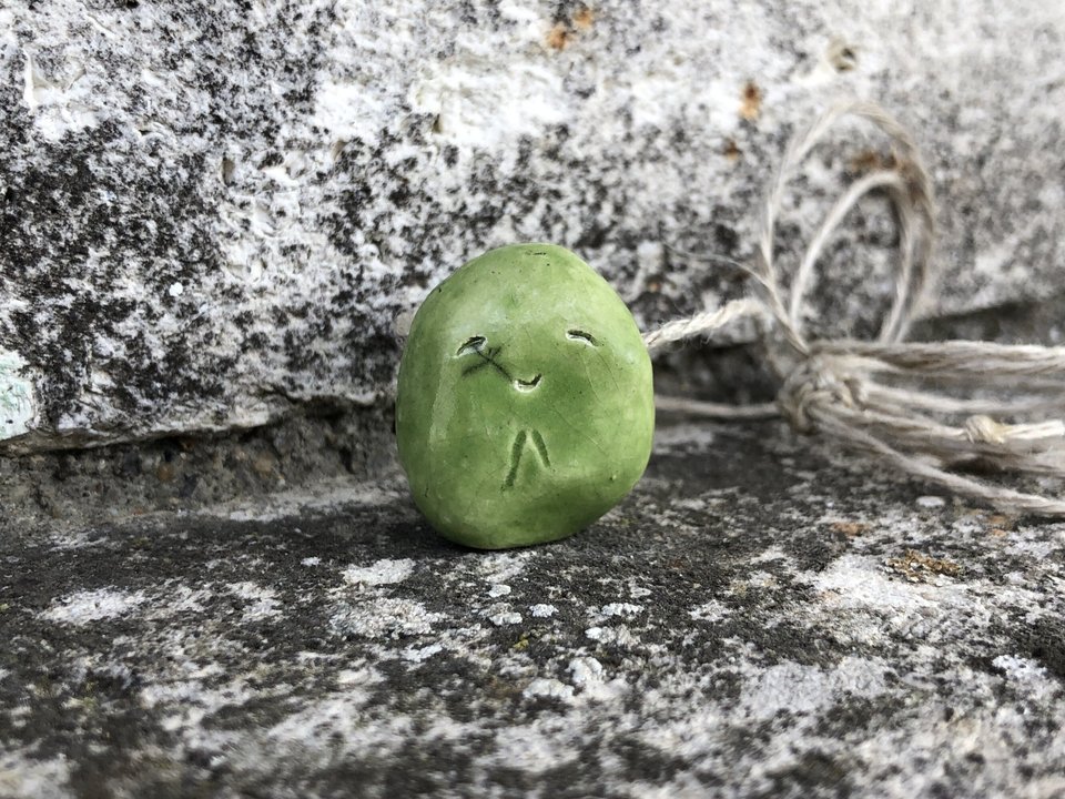 Simple raku ceramic Shinto Jizo pendant necklace glazed in spring green. Jizo has a kind, gentle face and is strung on a adjustable eco-hemp cord.