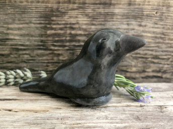 Raku ceramic sculpture of a sitting raven. It is glazed in dark grey, and its beak is left natural, unglazed black.