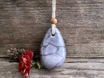 Raku ceramic worry pendant shaped a little like a bendy pear and glazed in light blue with hints of mauve. It has a sandalwood bead above it and is strung on a flax cord.